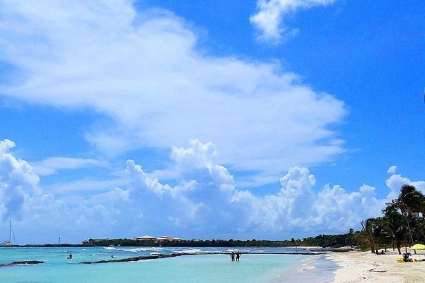 Plage de la côte caraïbe mexicaine avec un complexe hôtelier en arrière-plan, des cocotiers et une mer turquoise