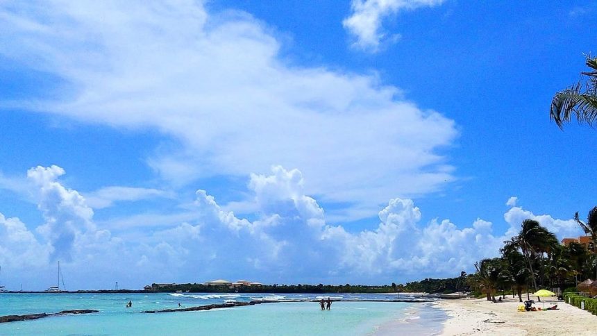 Plage de la côte caraïbe mexicaine avec un complexe hôtelier en arrière-plan, des cocotiers et une mer turquoise
